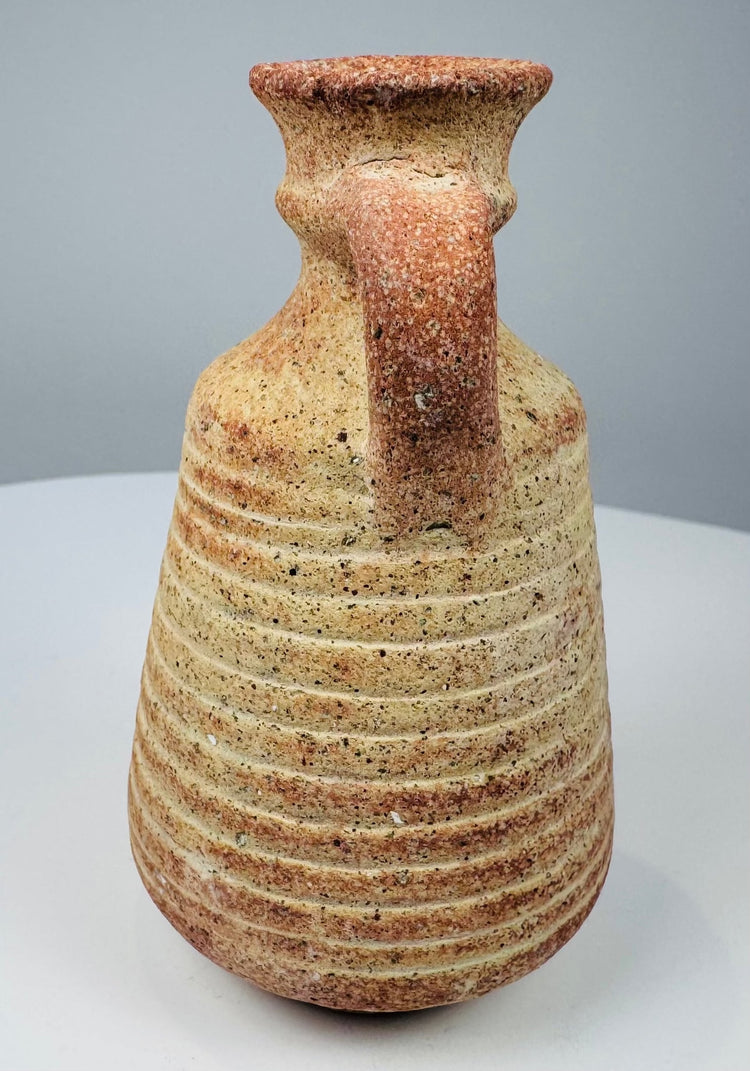 Side view of a Roman pottery vessel showing its rounded shoulder and loop handle