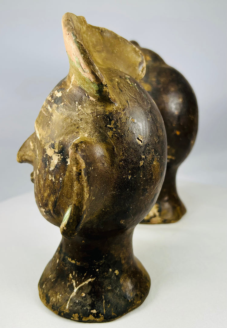 Hand-formed terracotta head sculptures with prominent ear ornaments and aged patina