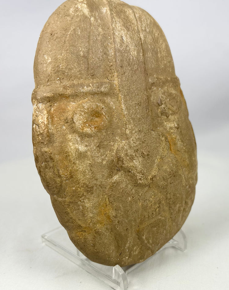 Primitive stone guardian face sculpture with recessed eyes and helmet ridge
