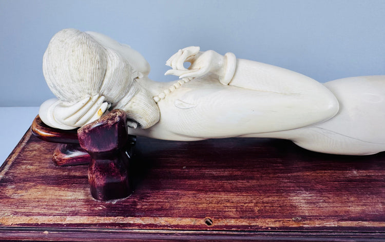 Front view of the reclining female figure showing her raised arm, carved jewellery and elongated pose
