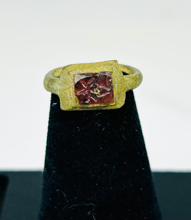Close-up of 2nd-century Roman bronze ring showing square bezel and red glass stone