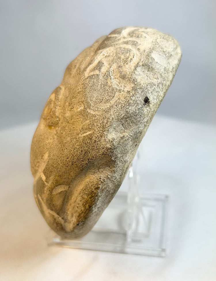 Folk art carved stone head with circular eyes and incised decorative border