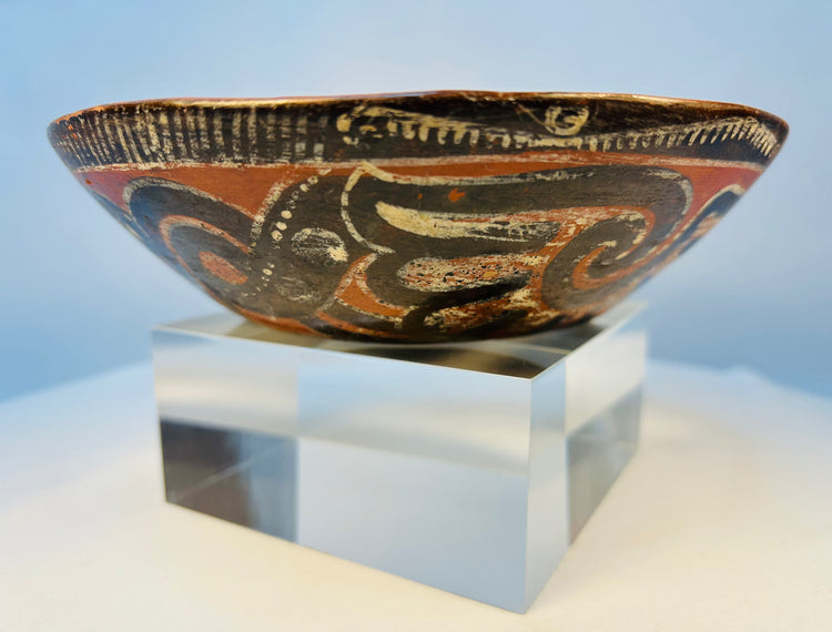Antique hand-painted Pre-Columbian pottery bowl displayed on clear museum stand