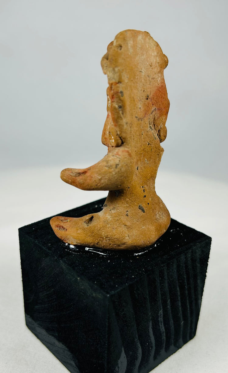 Seated Pre-Columbian terracotta figure from West Mexico with stylized features, pigment traces, and ancient patina