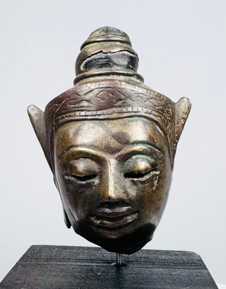 Antique Southeast Asian Buddha sculpture with meditative expression and decorative headdress