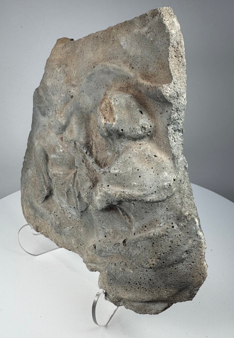 Reverse of Roman volcanic tuff relief fragment showing rough uncarved surface, porous stone texture and mineral deposits