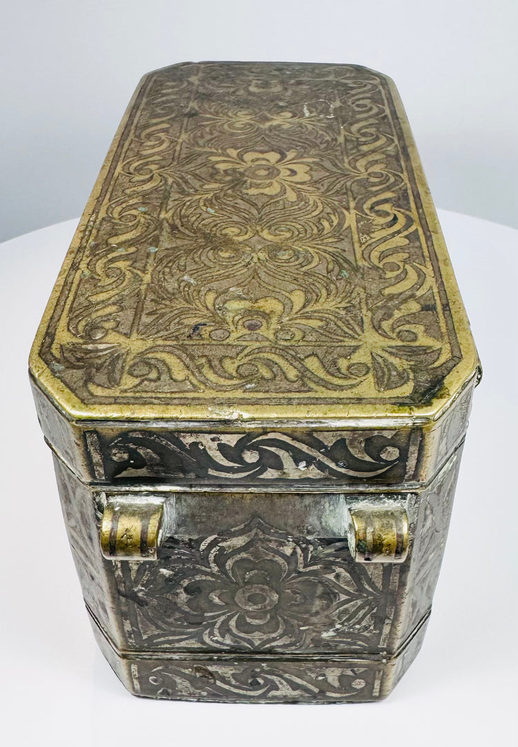 Top of a Philippine betel nut box displaying dense floral scrollwork and symmetrical brass-inlaid decoration across the lid.