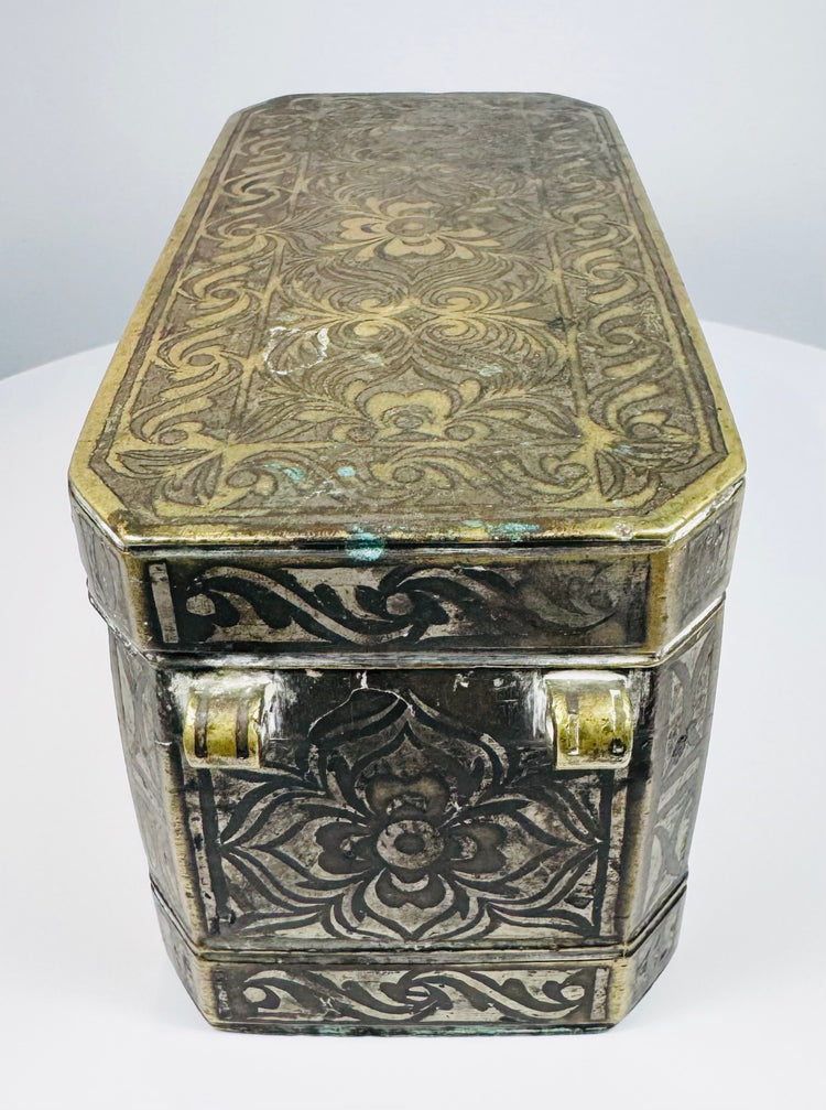 Side of a Mindanao betel nut box with ornate brass-inlaid floral motifs and naturally aged dark metal patina.