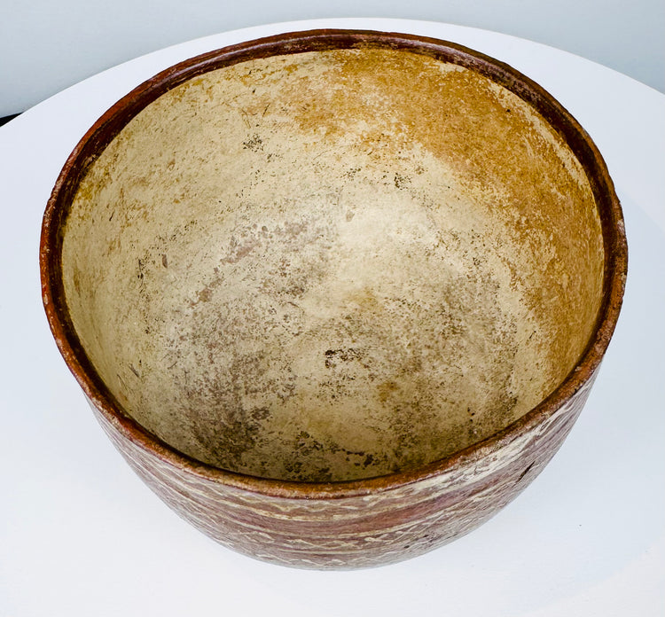 Geometric earthenware bowl with a broad open mouth and worn painted decoration.