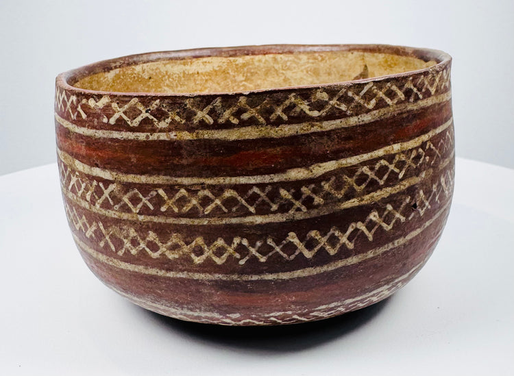 Bichrome ceramic bowl with repeating diamond motifs and visible surface wear.