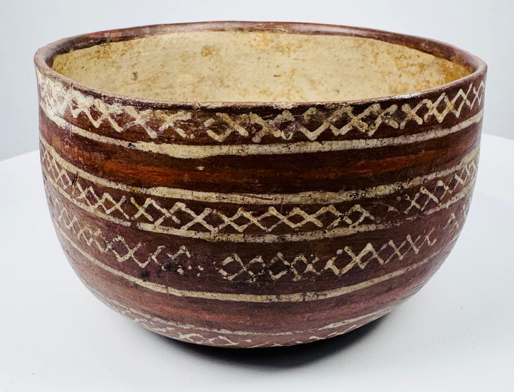 Decorated pottery bowl with cream geometric bands following its curved exterior.
