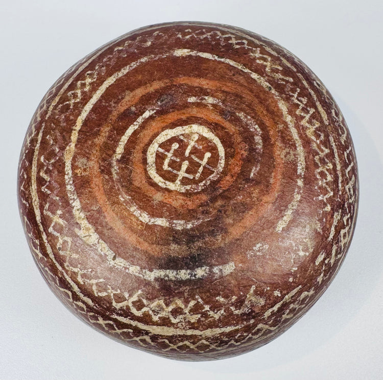 Ceramic bowl underside with concentric rings surrounding a central geometric motif.