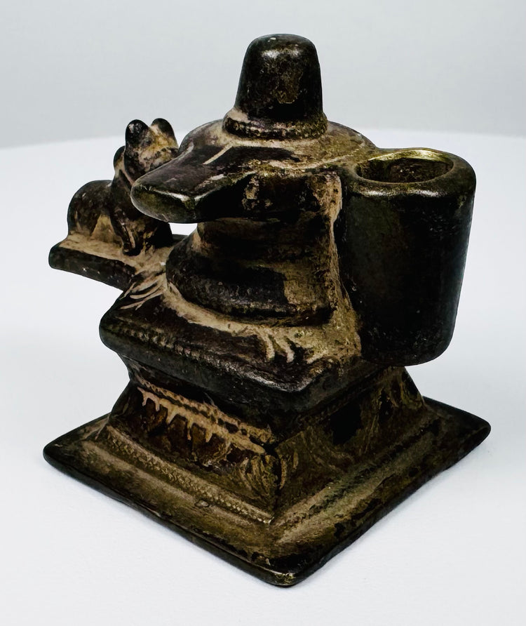 Indian Shaivite devotional object in cast brass with central Shiva Lingam and reclining Nandi bull.