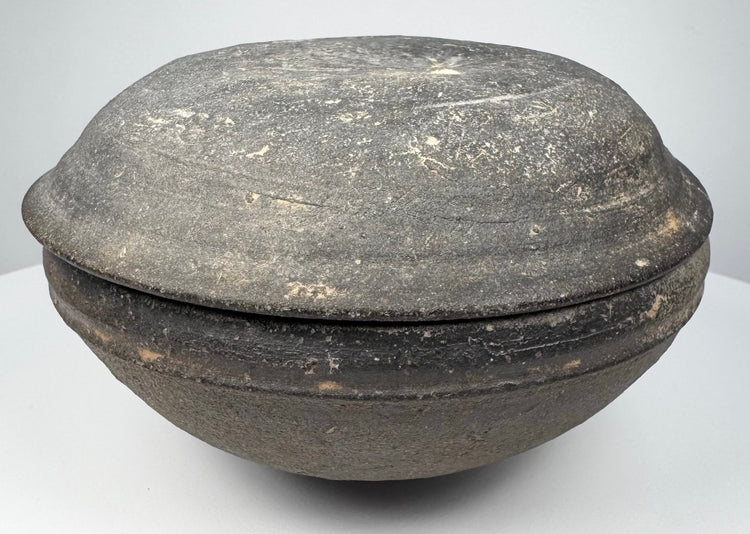 Tang Dynasty Chinese gray earthenware covered bowl in side profile, showing its compressed rounded form and fitted lid.