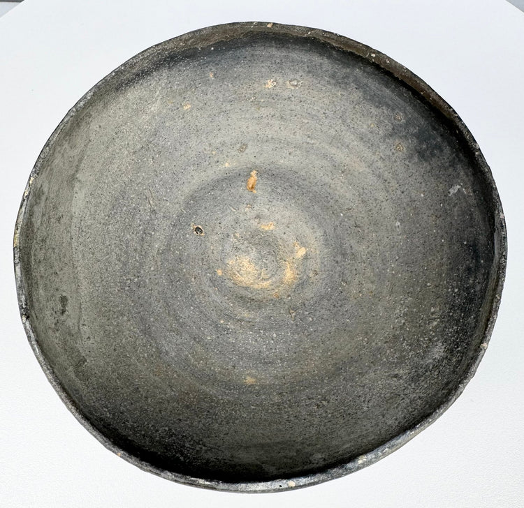 Interior of an ancient Chinese gray earthenware covered bowl showing visible concentric wheel-turning marks and lighter clay deposits.