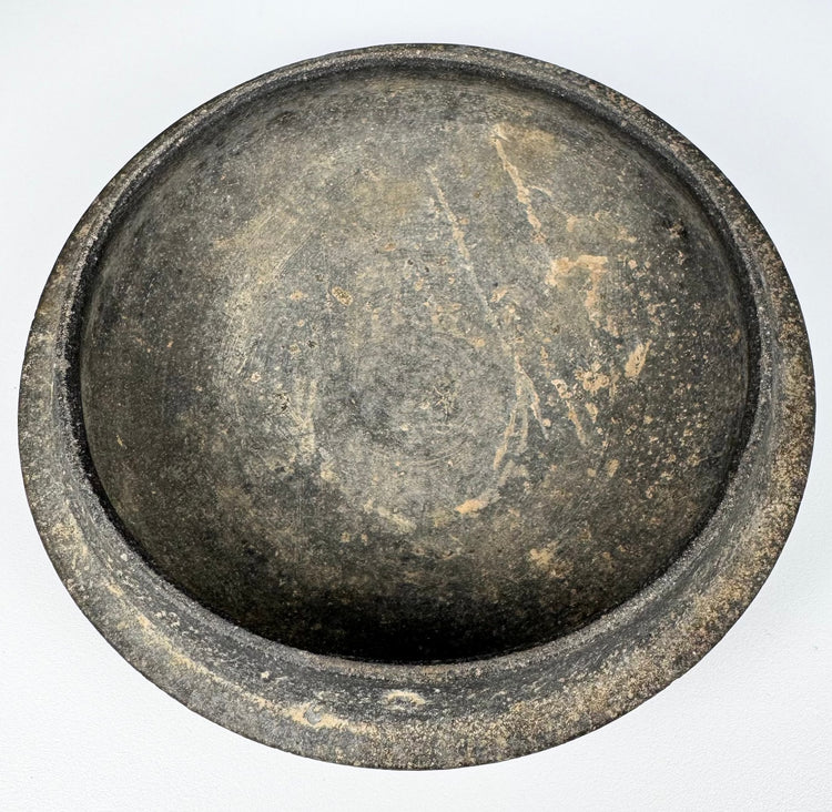 Interior view of the fitted gray pottery cover with rounded concave form, aged surface wear, and earthen accretions.
