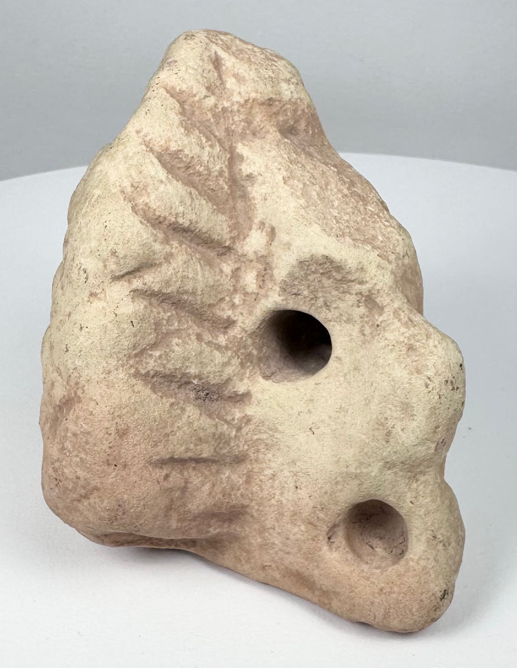 Carved Taíno zemi from the Caribbean with compact triangular body and central conical projection.