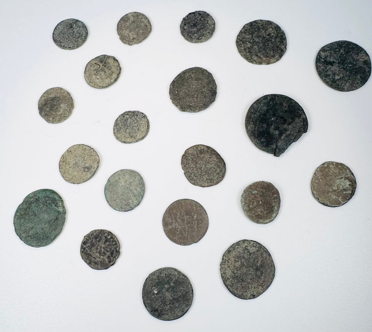 Ancient bronze coin collection showing heavily patinated surfaces, irregular edges, and surviving traces of imperial and reverse designs.