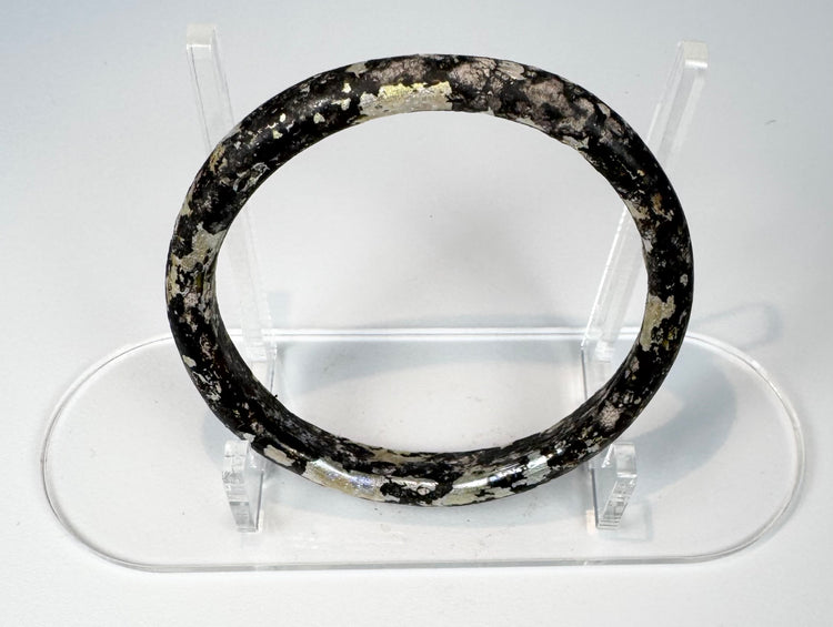 Close view of Roman glass bangle with pitting, exfoliation, and iridescent archaeological surface