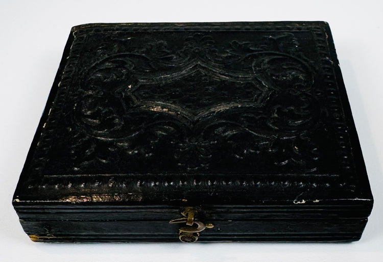 Closed mid-19th-century cased photograph with molded dark exterior, ornamental design, and metal clasp