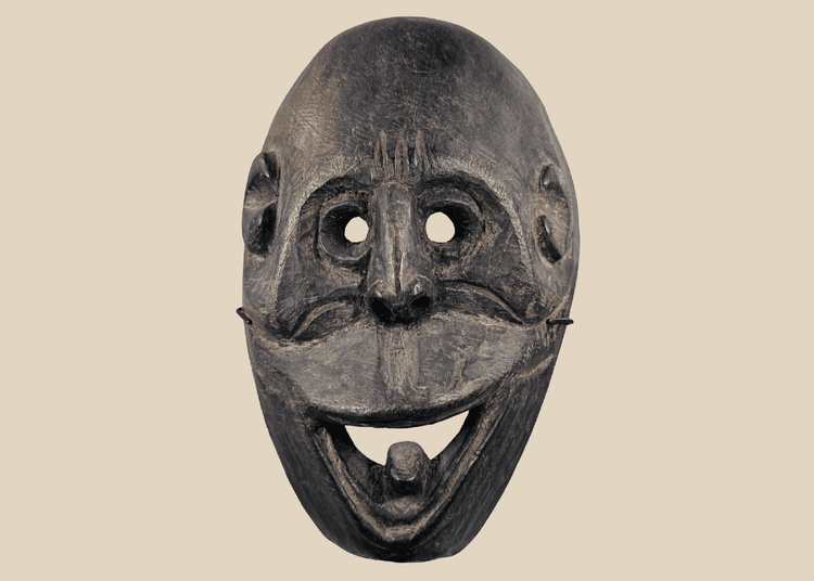 Carved wooden ritual mask from Fatuleu Village, West Timor, featuring large circular eyes and a protruding tongue, circa 1930.