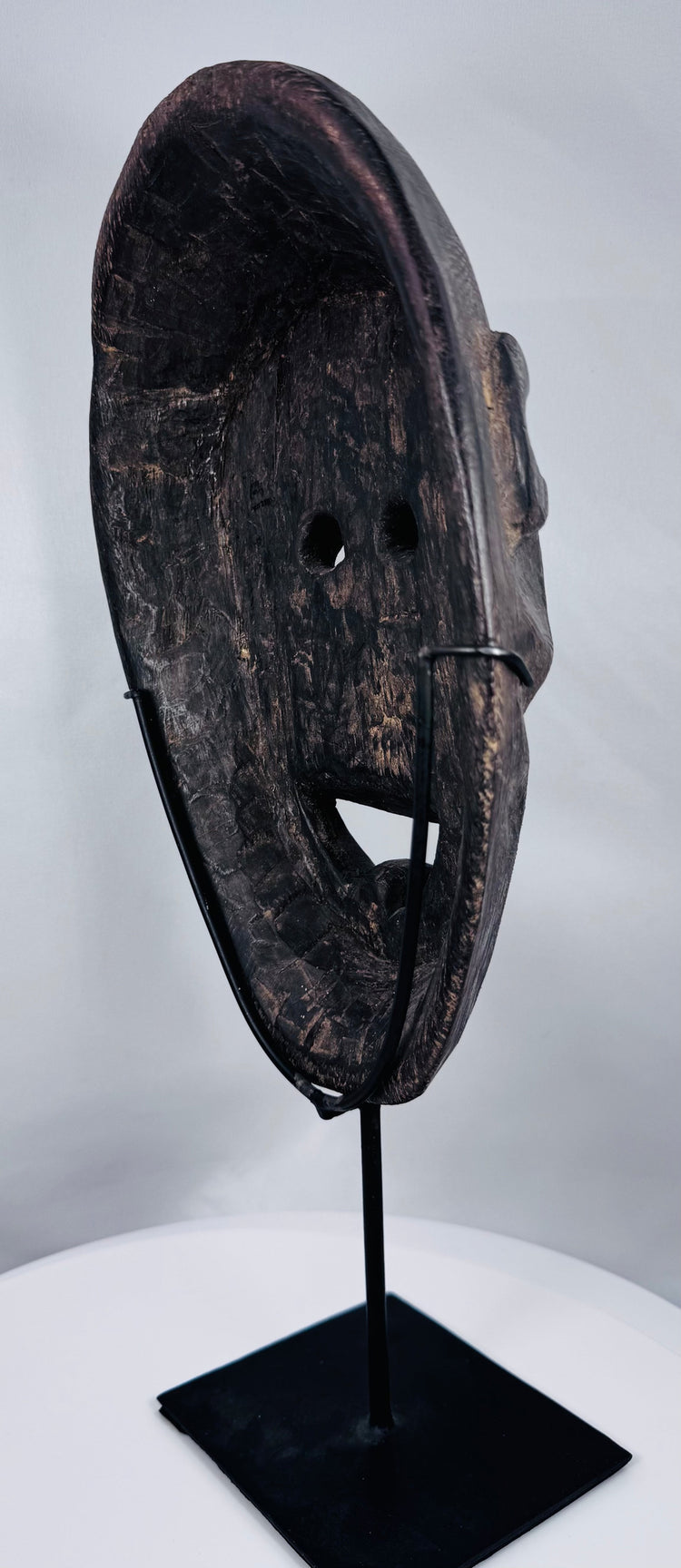 Traditional Timorese wooden mask with expressive monkey-like features and open mouth with protruding tongue.