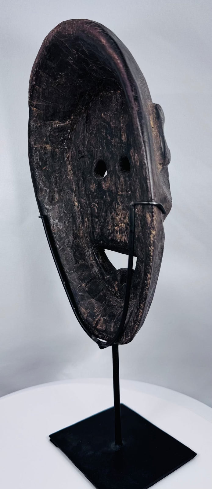 Traditional Timorese wooden mask with expressive monkey-like features and open mouth with protruding tongue.