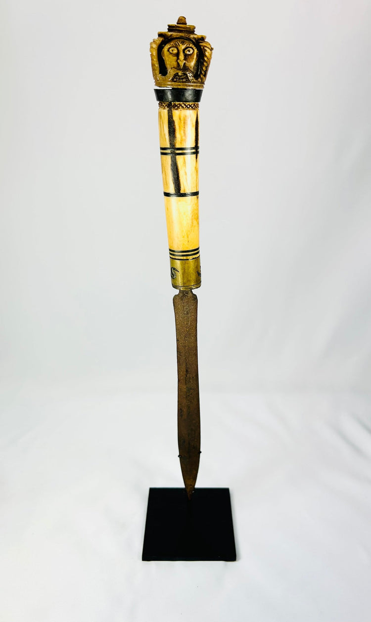 Indonesian Dayak knife handle showcasing ornate bone carvings and cultural motifs.