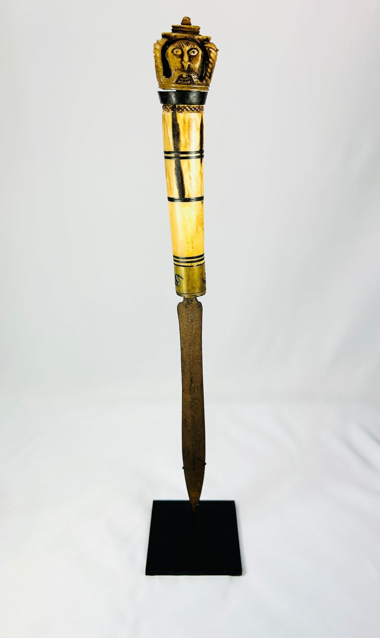 Indonesian Dayak knife handle showcasing ornate bone carvings and cultural motifs.
