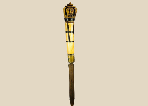 Indonesian Dayak knife from 19th century with carved bone handle depicting an Aso guardian beast and a male figure with elaborate mustache, steel blade, patinated surface, reflecting ritual and cultural significance of Borneo craftsmanship.