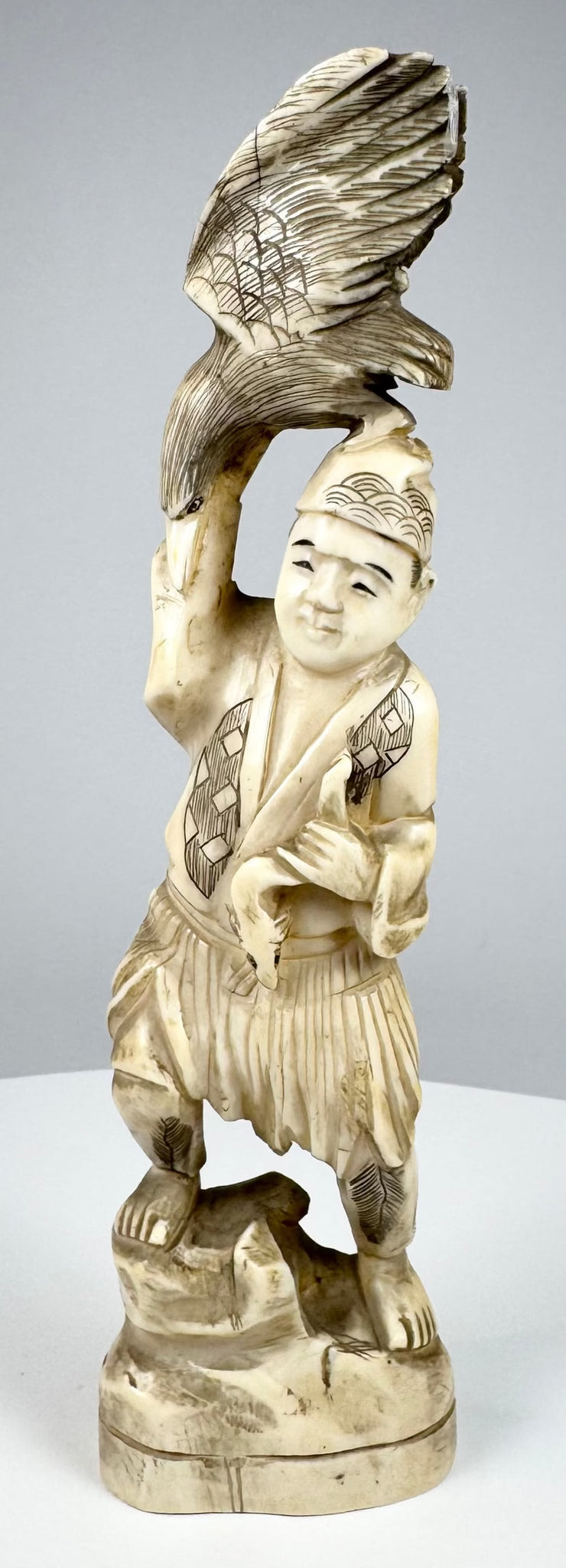 Three-quarter view of an antique Japanese falconer sculpture with spread-wing bird