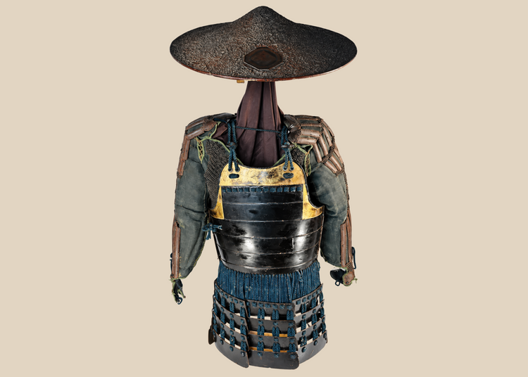 Authentic Japanese samurai armor from the Muromachi Period (1333–1573), featuring black-lacquered cuirass with gold accents, kote sleeves with chainmail reinforcement, dark-blue silk lacing, and a lacquered jingasa war hat bearing the Takeda clan crest, displayed on a wooden stand.