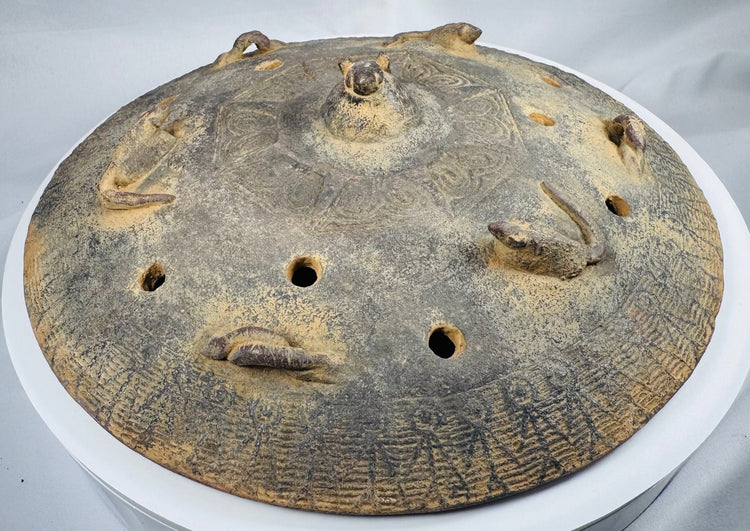 Front view of an ancient Chinese tripod ritual vessel with a removable pierced lid and raised handles.