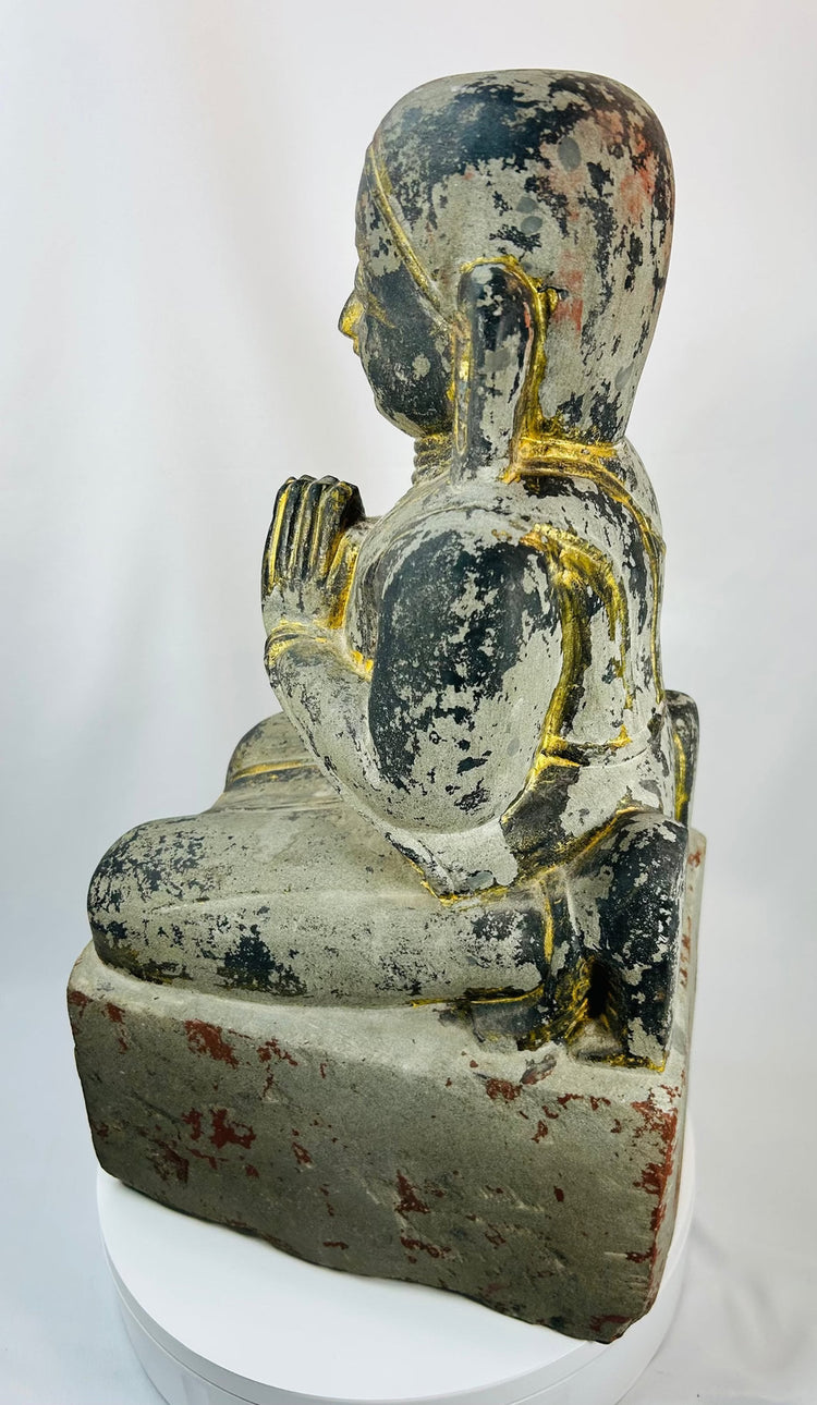 Burmese temple sculpture of a kneeling worshipper with elongated ears and serene expression.