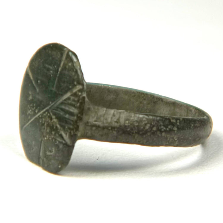 Close-up of Byzantine bronze signet ring with weathered incised cruciform bezel and naturally aged surface