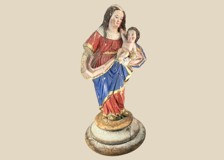 Spanish Colonial Madonna and Child statue, circa 1780–1820, hand-carved wood with original polychrome and gilding. Virgin in red and blue robes with gilt highlights holds infant Christ with golden orb. Mounted on original socle with craquelure and age wear.