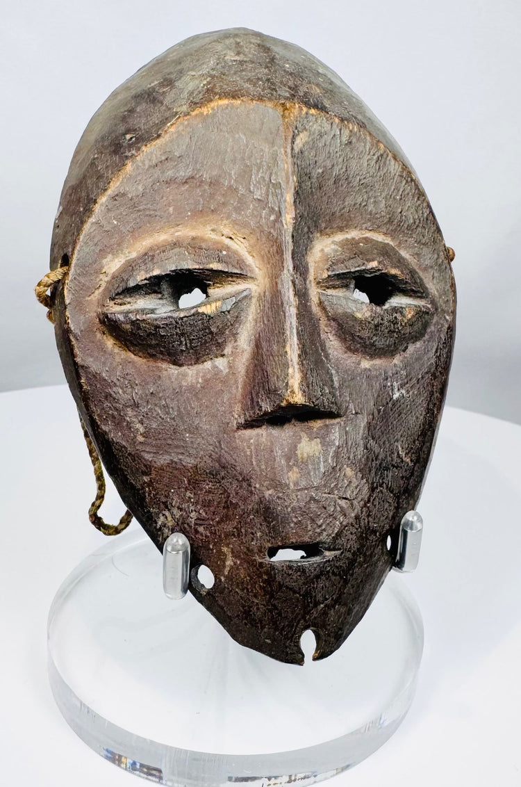Mid-20th century Lega passport mask with triangular nose, understated mouth, and ritual wear.