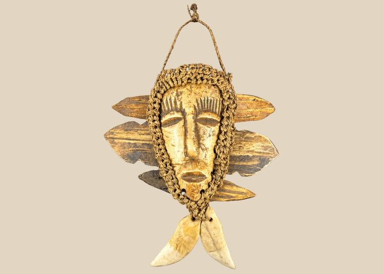 Mid-20th-century Lega tribal pendant mask from the Congo, carved bone face with braided fiber collar, wood backing, and hanging cord, displayed on a black stand against a white background.