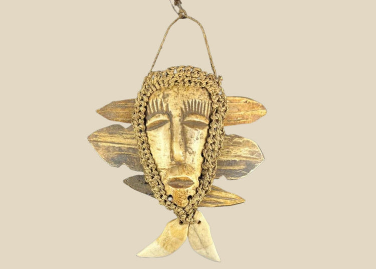 Mid-20th-century Lega tribal pendant mask from the Congo, carved bone face with braided fiber collar, wood backing, and hanging cord, displayed on a black stand against a white background.