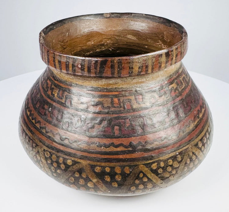 Side view of ancient Mesoamerican redware bowl showing horizontal geometric bands and dotted triangular motifs