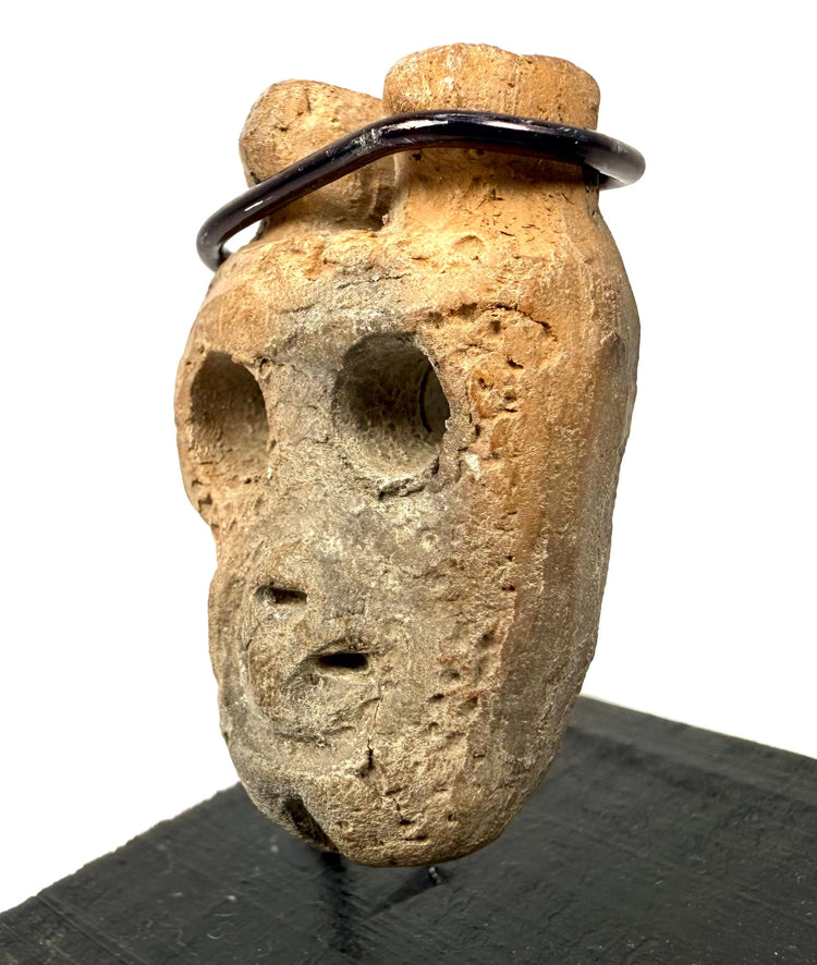 Three-quarter angle of ancient West Mexican bone mask pendant showing nose ridge and eye sockets