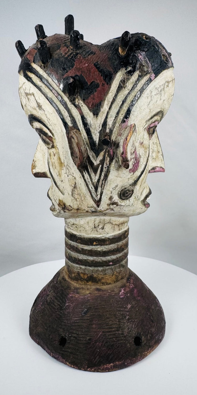 Traditional Igbo masquerade crest with opposing faces, projecting coiffure elements, and aged patina.