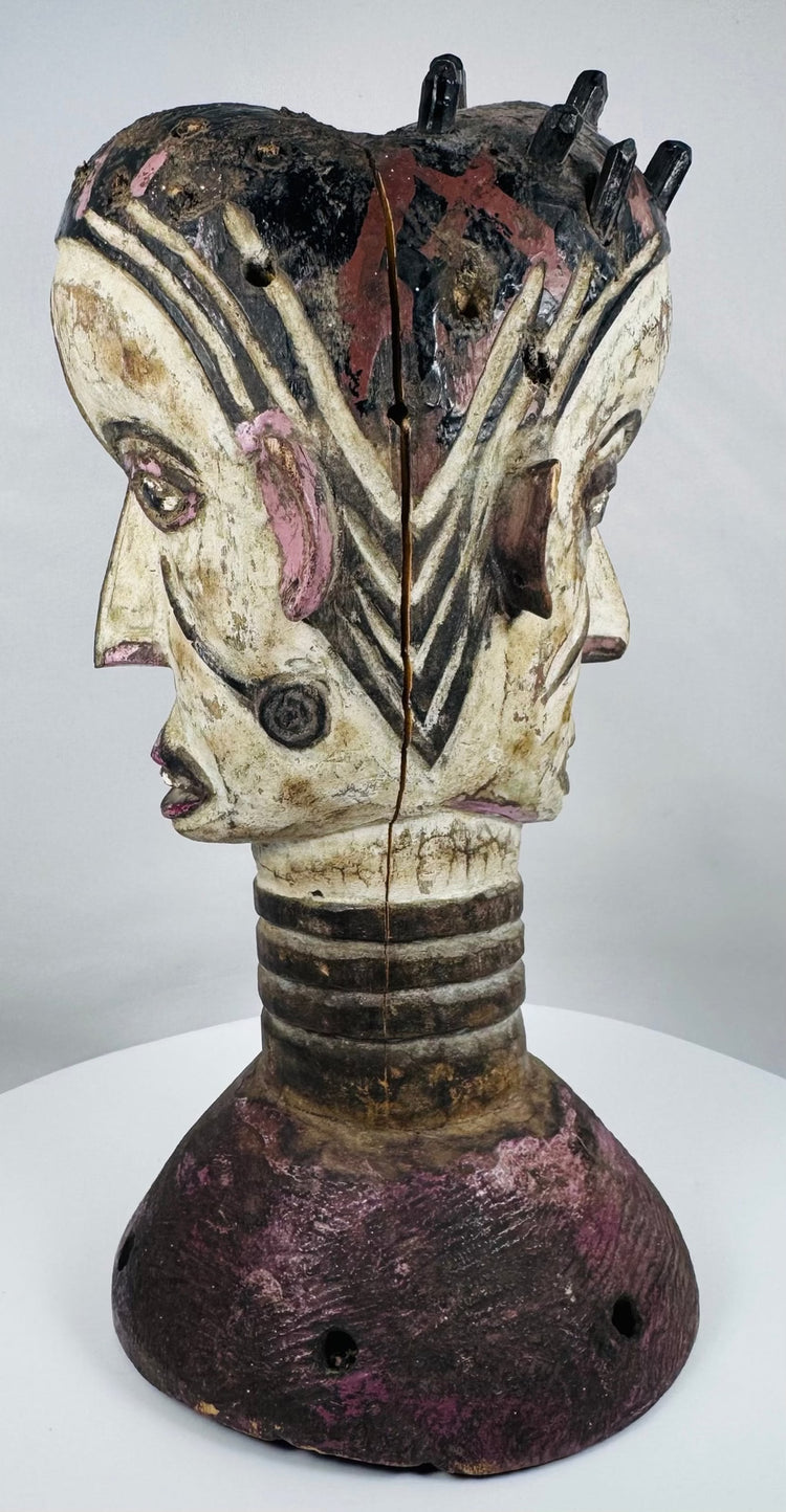 Mid-century Igbo masquerade headdress featuring a carved Janus head design and weathered surface patina.