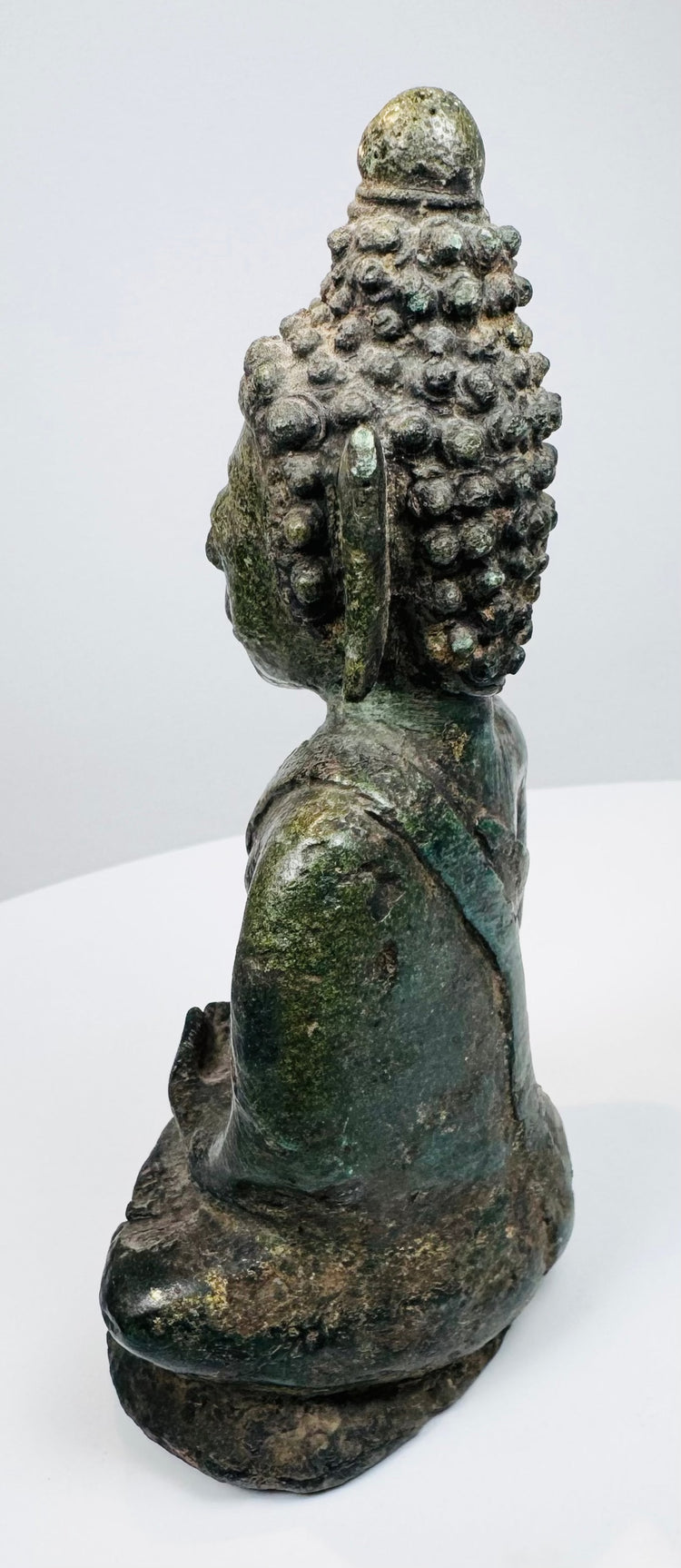 Side view of the hollow-cast Thai bronze Buddha with aged verdigris patina