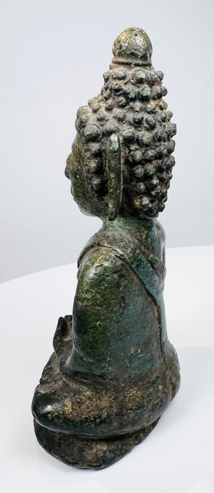 Side view of the hollow-cast Thai bronze Buddha with aged verdigris patina