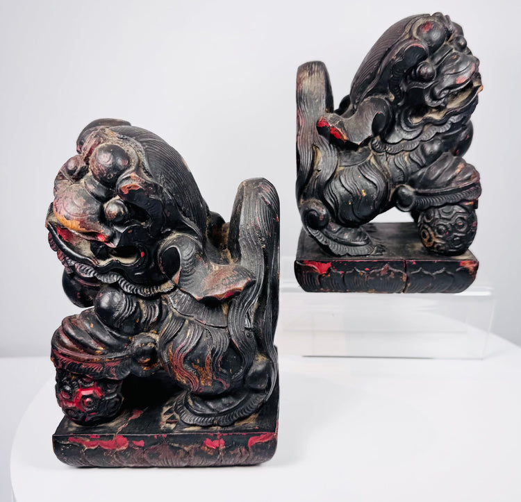 Antique Chinese Foo dog pair in mirrored poses with raised paws resting on patterned brocade balls