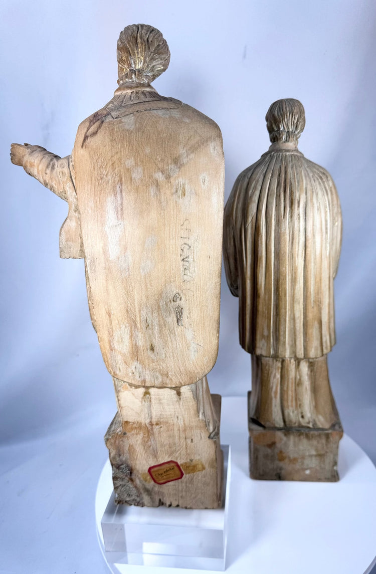 Hand-carved Christian saint figures in wood featuring detailed vestments and expressive facial features.