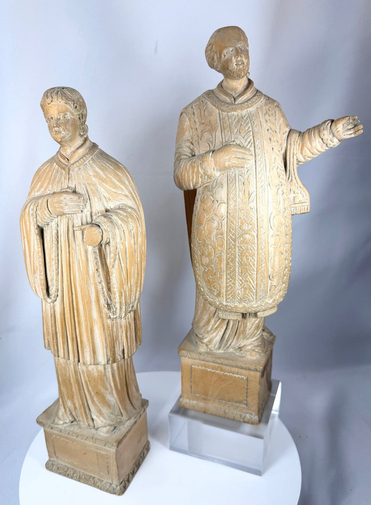 Antique religious carvings with finely detailed robes, integral bases, and warm aged wood surfaces.