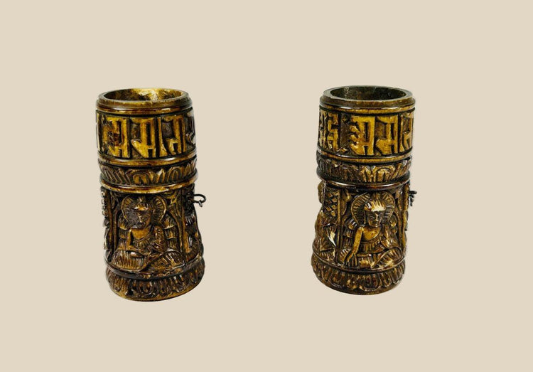 Pair of small Tibetan Buddhist prayer wheels carved from human femur bone, each 3.1 in tall, featuring three relief Buddha figures and a band of Sanskrit inscriptions, used for ritual prayer and meditation.