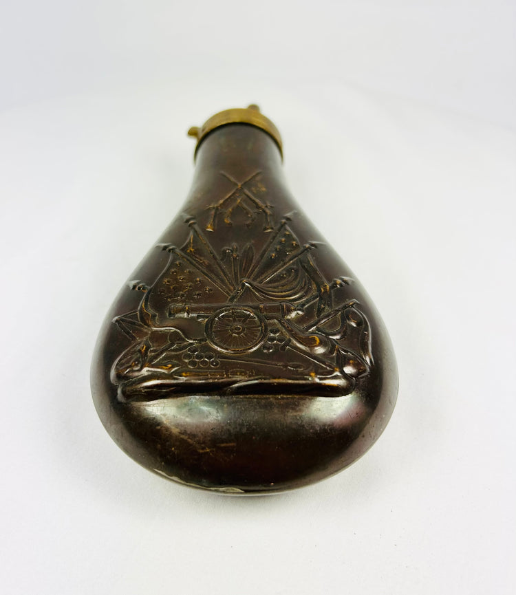19th century American powder horn style flask in embossed copper with military stand of arms decoration, chocolate brown patina, collectible firearms accessory.